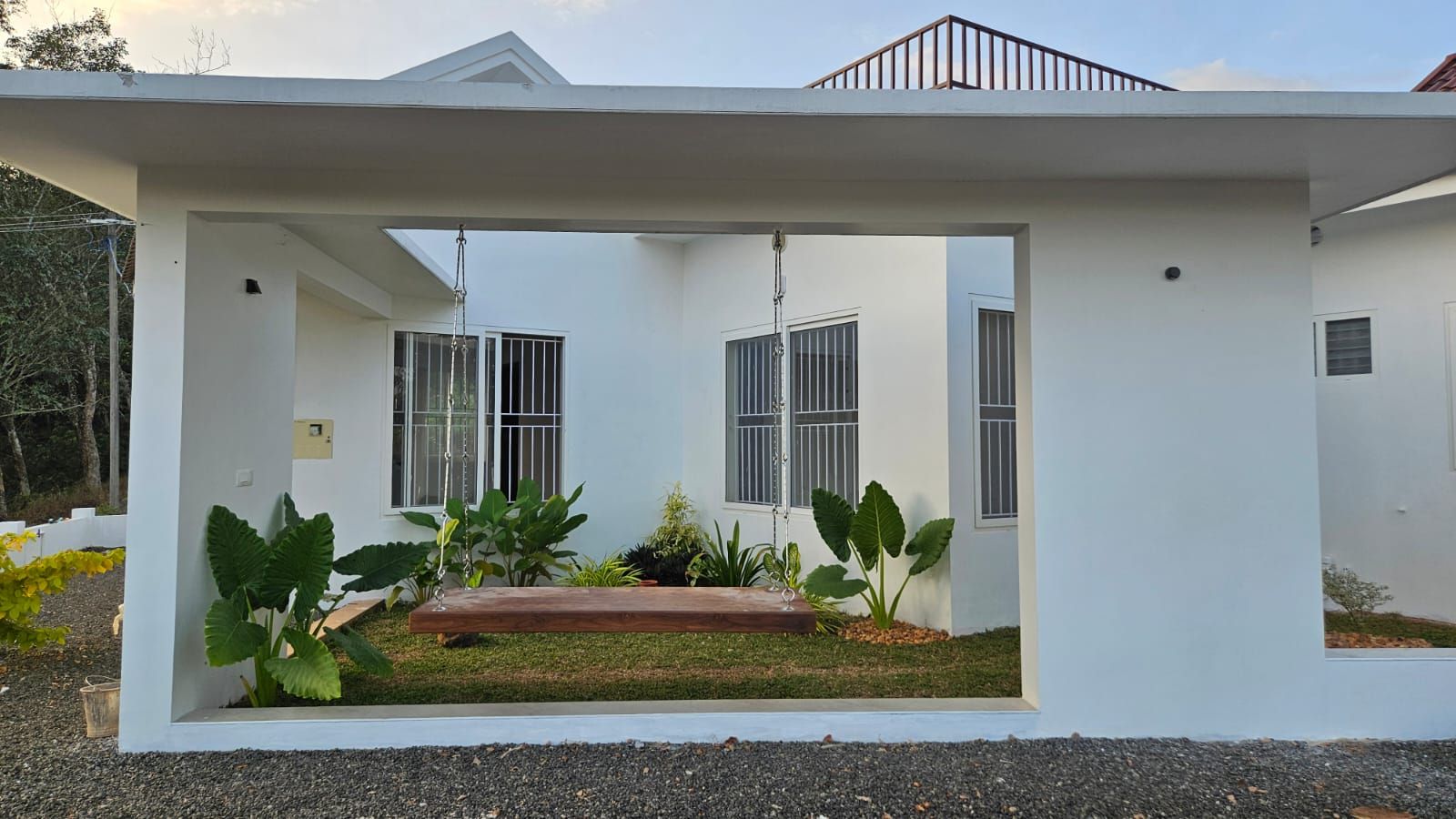 A large rectangular opening in the home's exterior, perfectly framing the serene inner courtyard and swing.