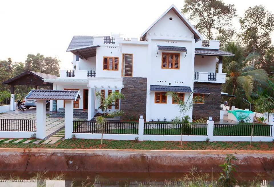 Exterior view of a multi-storey contemporary home with white walls, stone cladding, and a gabled roof.
